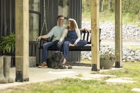 Couple sitting on a porch swing with a dog at their feet