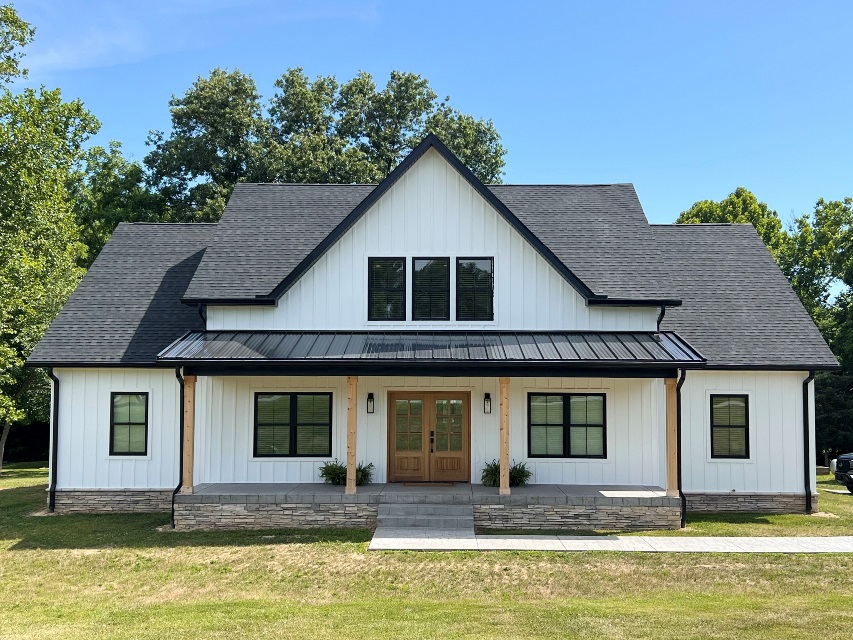 White farmhouse-style home with a black roof after building a home on family land.