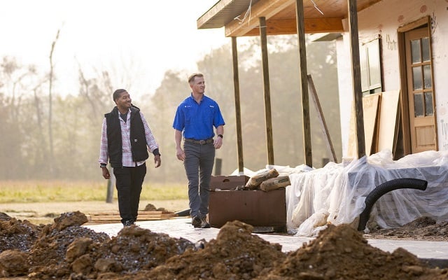 A Rural 1st loan officer and his client walking in front of a new rural home that's under construction.