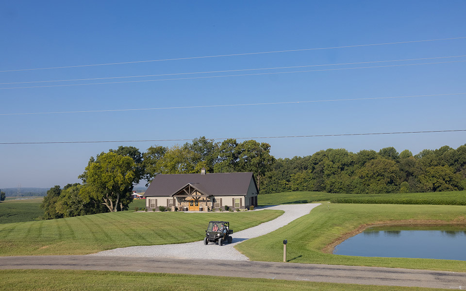 A utility vehicle driving down the driveway of a newly built rural home.