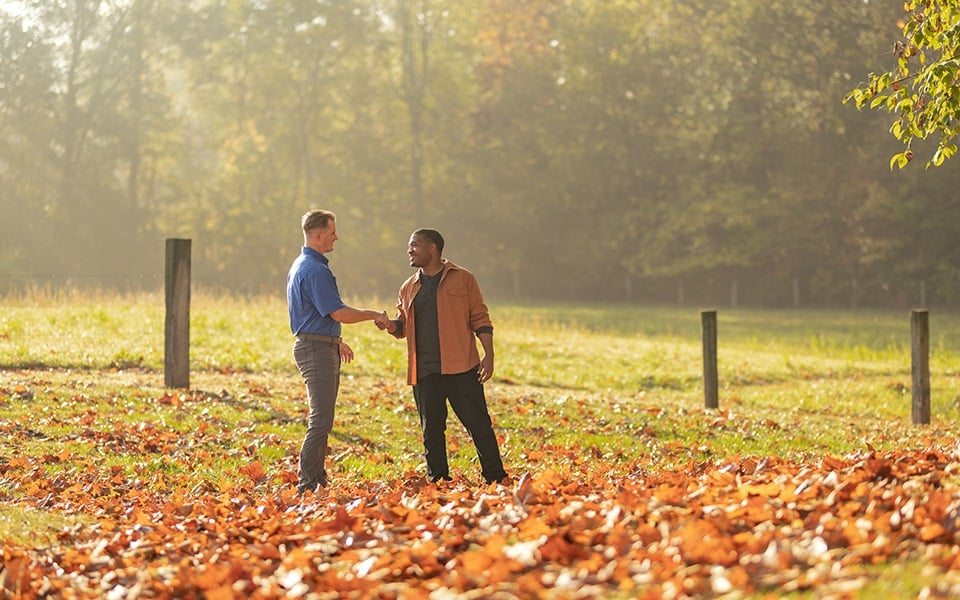 A man and his Rural 1st loan officer shaking hands on his new rural property.