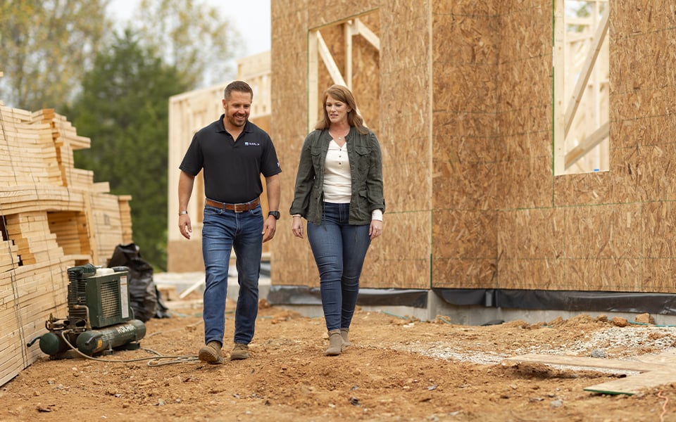 A Rural 1st loan officer and a client walking through the site of a new home being constructed discussing construction loans.