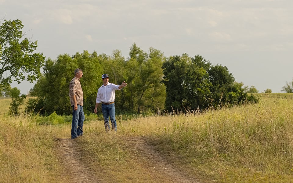 Two people standing on a rural plot of bare land bought with land loans from Rural 1st.